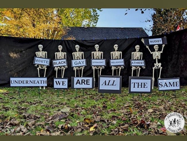 Row of skeletons holding labels that read underneath we are all the same.