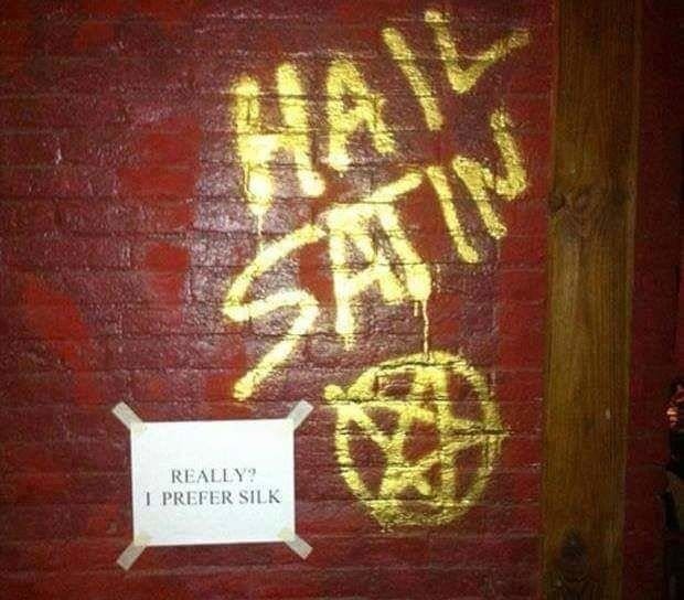 Hail Satan graffiti on brick, answered by a taped note saying really, I prefer silk.
