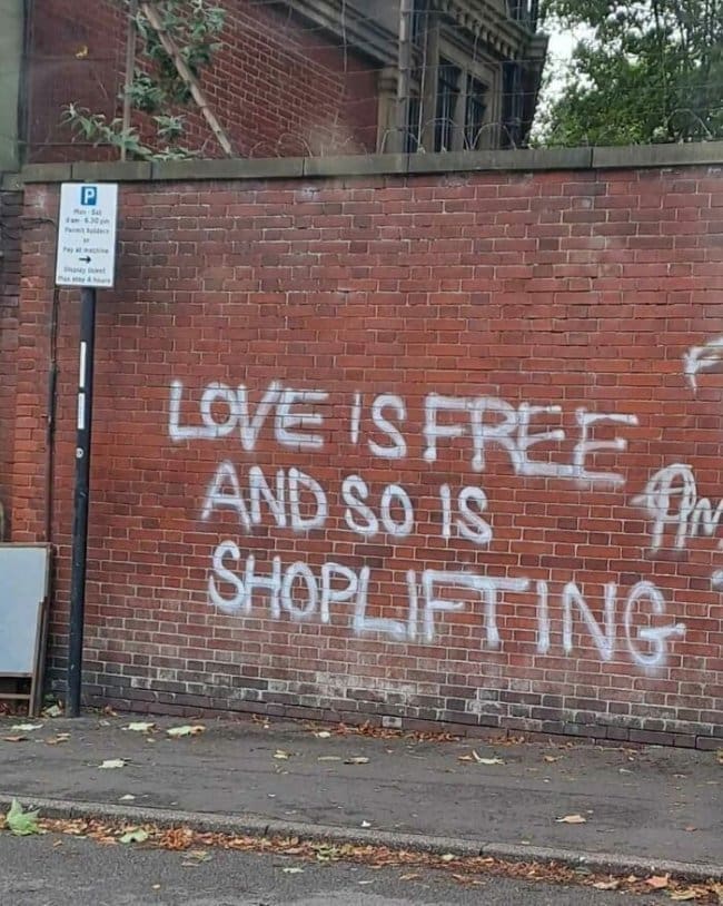 Thoughtful graffiti on a brick wall saying love is free and so is shoplifting.