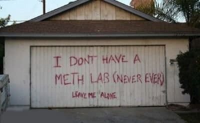Garage door spray painted with a frantic denial of having a meth lab.