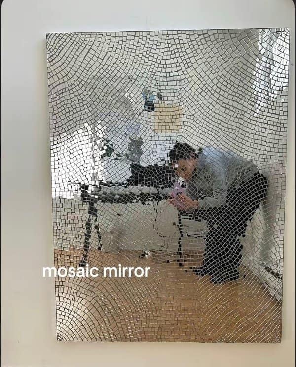 Mosaic mirror of tiny silver tiles, one of the unique designs, reflecting someone at a desk.