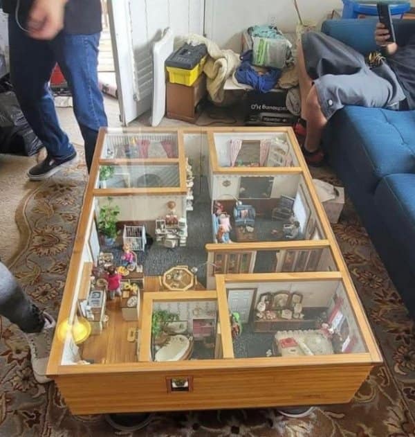 A glass top coffee table with a full dollhouse inside, every room furnished in miniature.