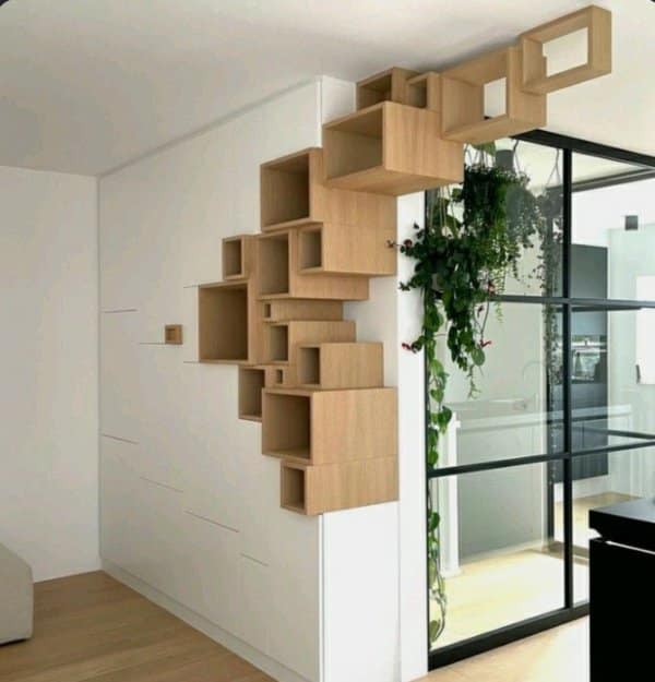 Wooden box shelves arranged in a staggered staircase pattern up a white wall beside a glass door.
