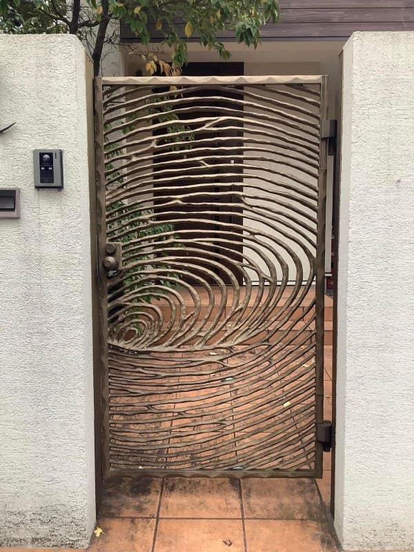 A metal front gate with swirling bars shaped like tree rings or a giant fingerprint.