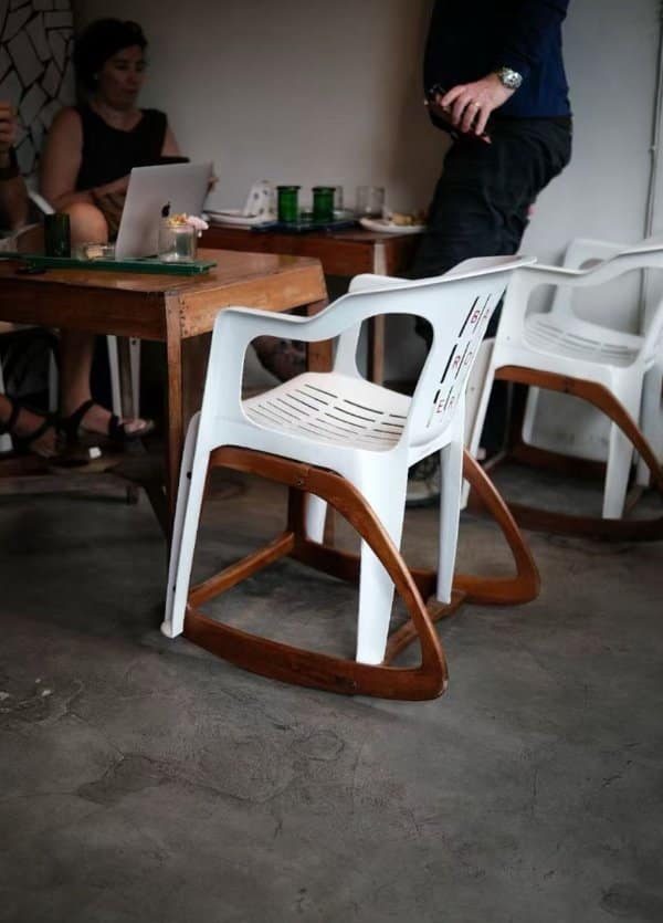 Unique designs at a cafe: white plastic patio chairs fitted with curved wooden rocking runners.