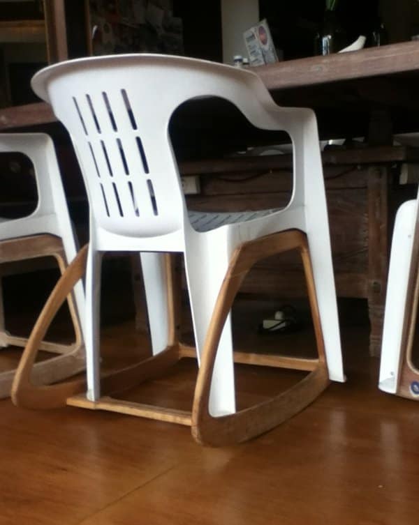 Side view of a plastic patio chair converted into a rocker with bent wooden runners.