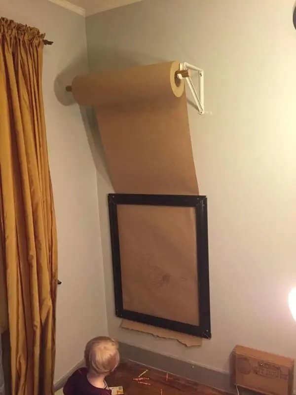 Brown kraft paper roll mounted on a wall above a frame as a drawing station for a toddler.