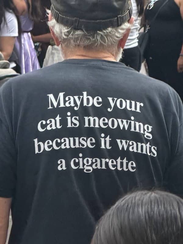 Older man wearing a shirt saying maybe your cat is meowing because it wants a cigarette