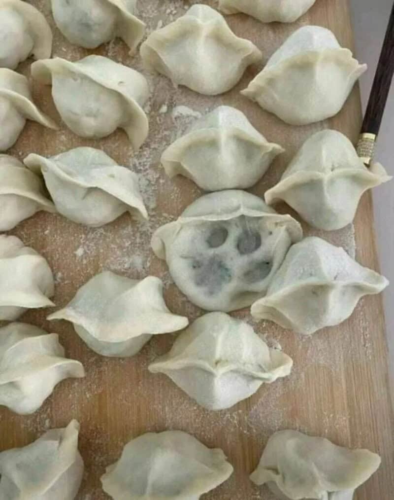 Tray of homemade dumplings where one has a perfect cat paw print pressed into it.
