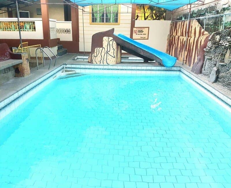 Bright blue swimming pool so still and clear it looks like an empty tiled floor.