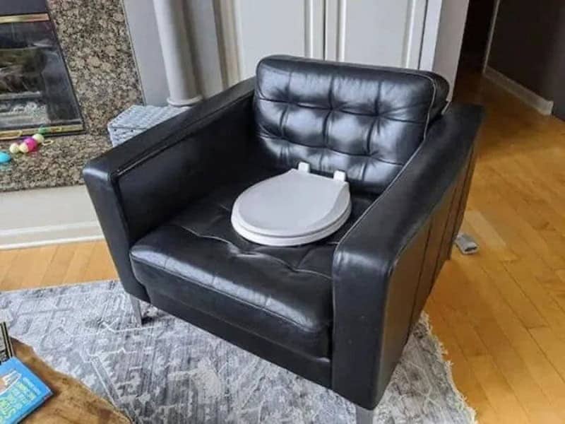 Black leather armchair with a white toilet seat resting on the cushion, one of many wait what memes.