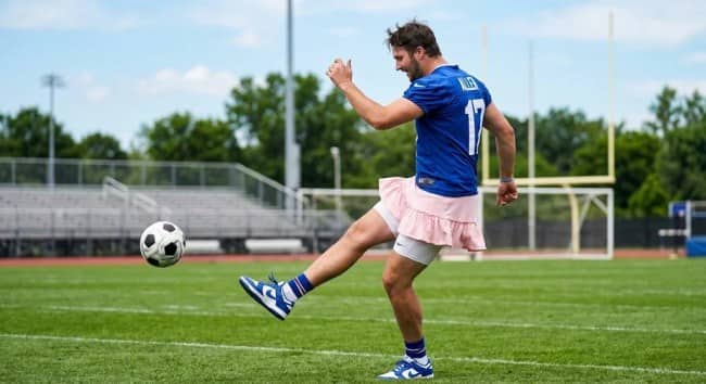 Bills player in a number 17 jersey and pink tutu kicking a soccer ball.