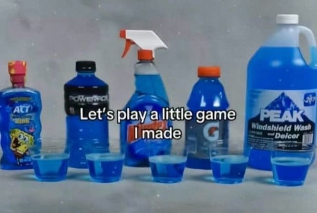 Five cups of blue liquid in front of sports drinks, glass cleaner, and windshield fluid.