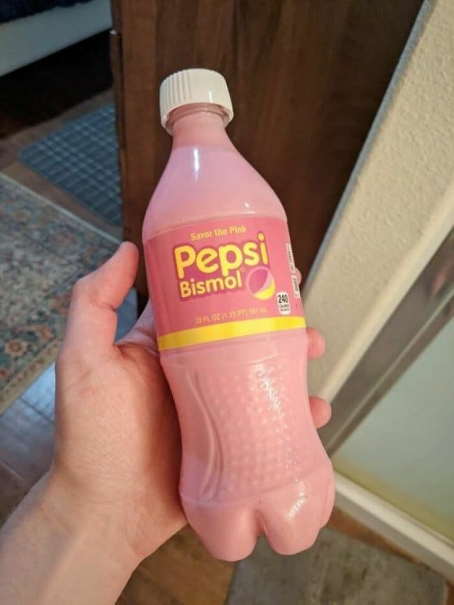 Hand holding a pink bottle labeled Pepsi Bismol, a soda and stomach medicine mashup.