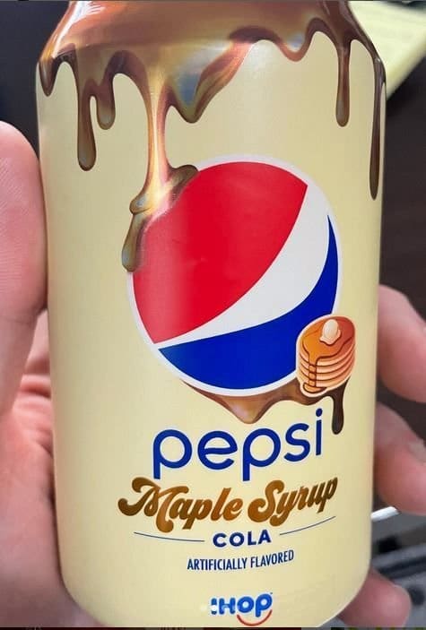 Hand holding a cream colored Pepsi Maple Syrup Cola can decorated with dripping syrup and pancakes.