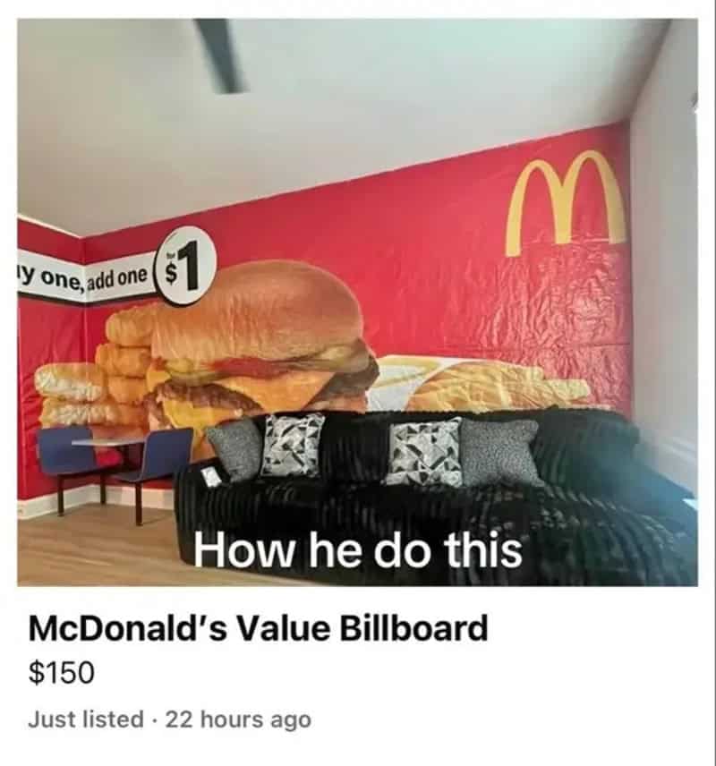 Living room with a giant McDonald's billboard used as wallpaper behind a black sofa.
