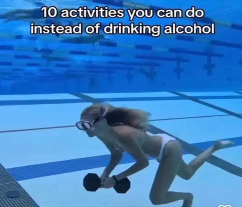 Woman in goggles carrying a dumbbell along the bottom of a swimming pool.