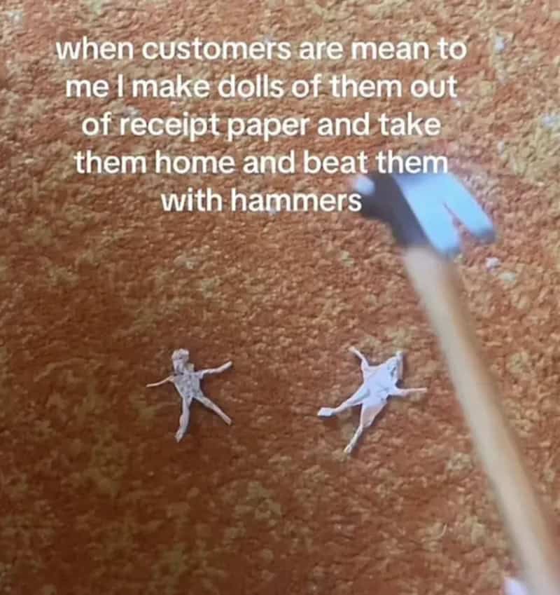 Tiny dolls cut from receipt paper lying on a carpet next to a small toy hammer.