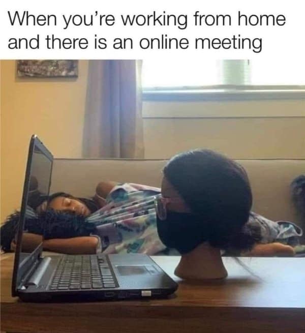 Mannequin head in a face mask propped at a laptop while the worker naps on the couch.