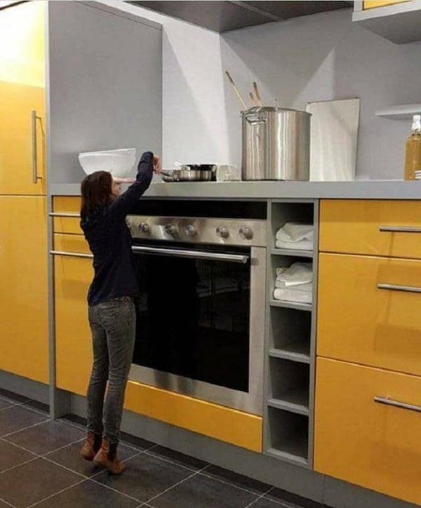 A woman cooking in a kitchen with hilariously oversized countertops and appliances.