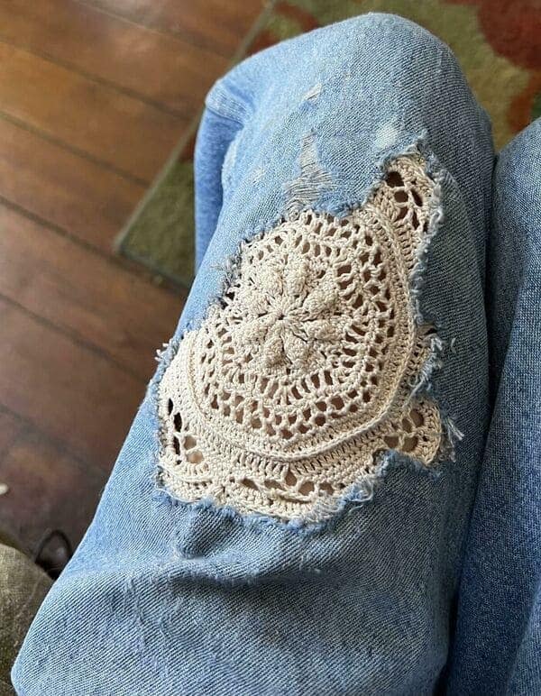 Crochet doily patch on ripped blue jeans