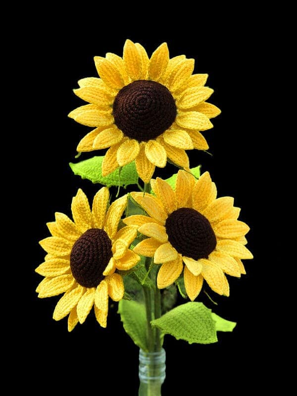 Trio of crocheted sunflowers in a bouquet on black background