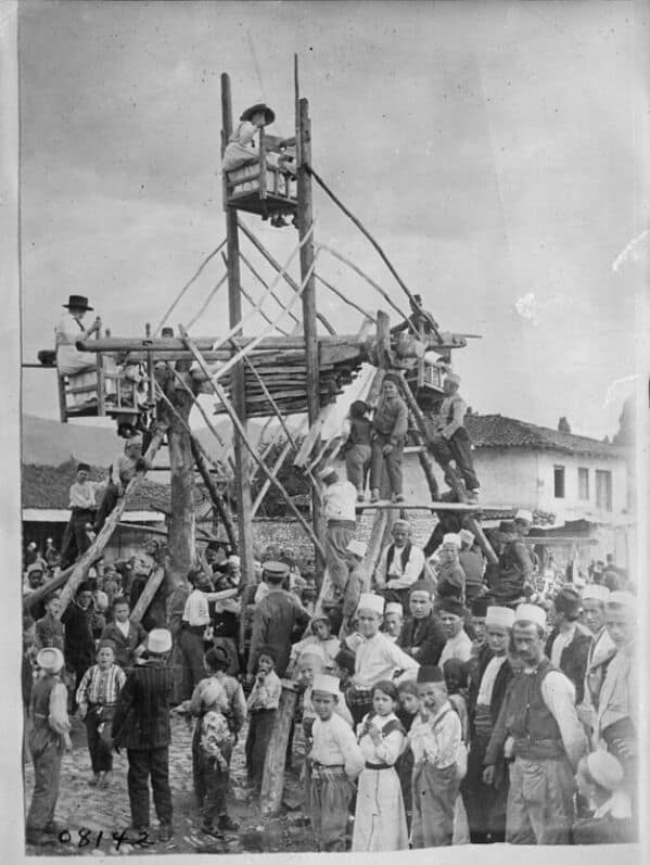 A vintage photo of a massive, rickety, and extremely dangerous-looking wooden swing set at a community fair.