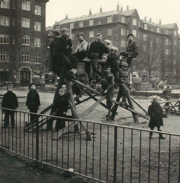 A vintage photo of a crowded and very tall wooden jungle gym from a dangerous city playground of the past.