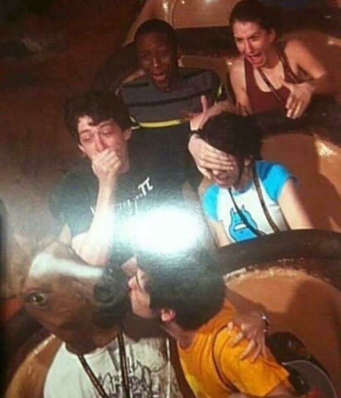 A cursed rollercoaster photo of someone in a creepy horse mask kissing a man while others scream in terror.