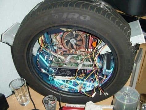A highly creative and dangerous custom PC build where all of the computer's components have been installed inside of a car tire.