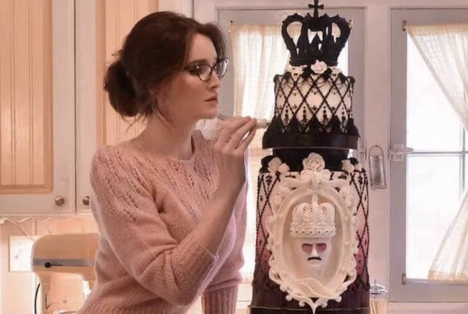 Talented baker finishing a highly detailed gothic black and white tiered cake with crown toppers.
