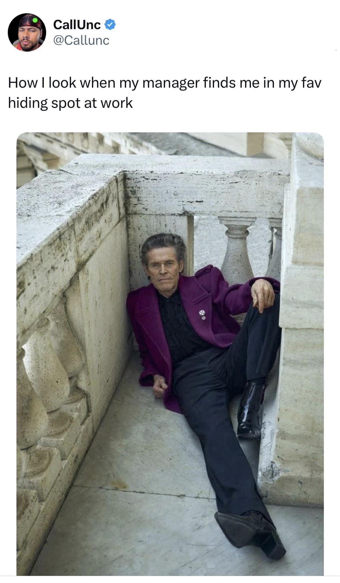 A classic meme featuring Willem Dafoe in a high-fashion purple suit, hiding in the corner of a white stone balcony, captioned as the face you make when your manager finds your favorite work hiding spot.