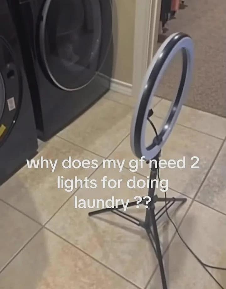 A large ring light setup positioned directly on a laundry room floor in front of a washing machine captures a domestic mystery on a viral classic meme template.