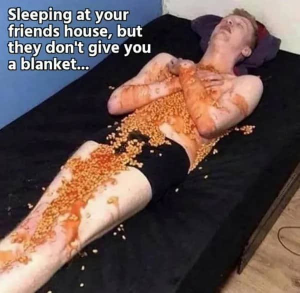Man sleeping on a bed covered in baked beans, captioned about friends not providing a blanket.