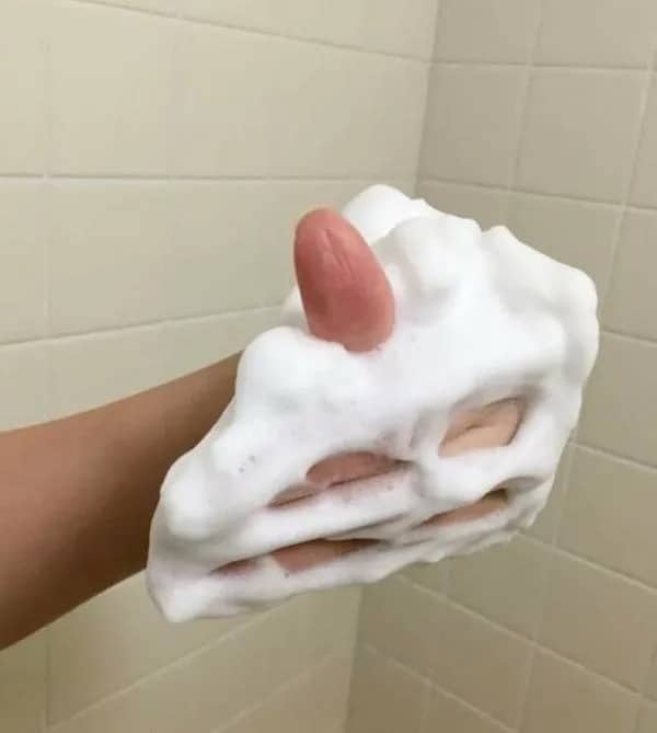 Hand covered in thick soap foam with fingers poking through, resembling a slice of white cake.