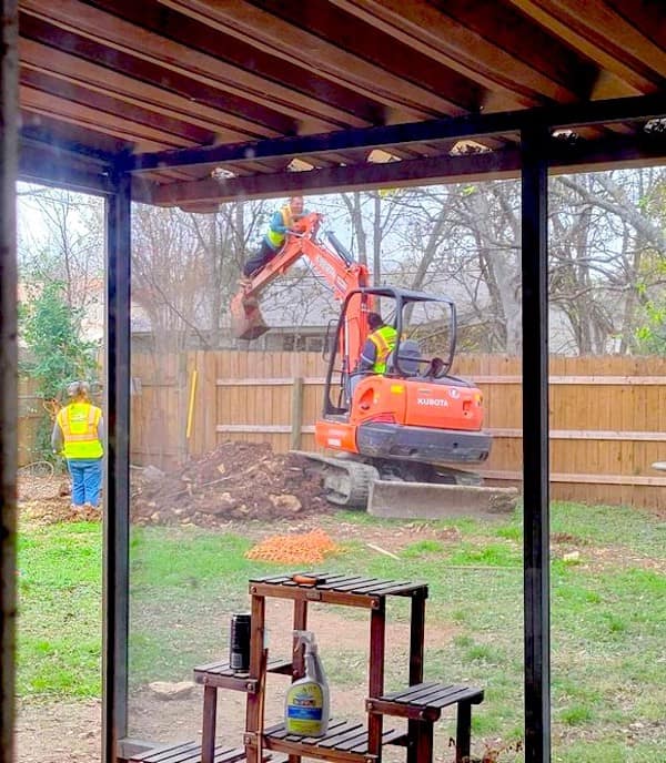 A safety third special showing a construction worker in a high-vis vest literally surfing on the hydraulic arm of a moving orange excavator to reach a tree branch.