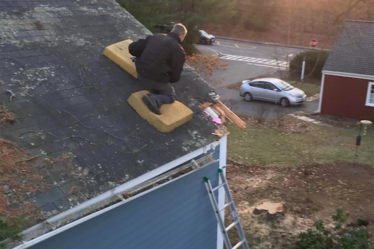 Safety third gallery capturing the absolute peak of workplace precariousness, featuring a green scissor lift balanced on a floating pool platform, a dad cleaning a shotgun while his daughters get ready for prom, and a ladder balanced on a bench on a flight of stairs.