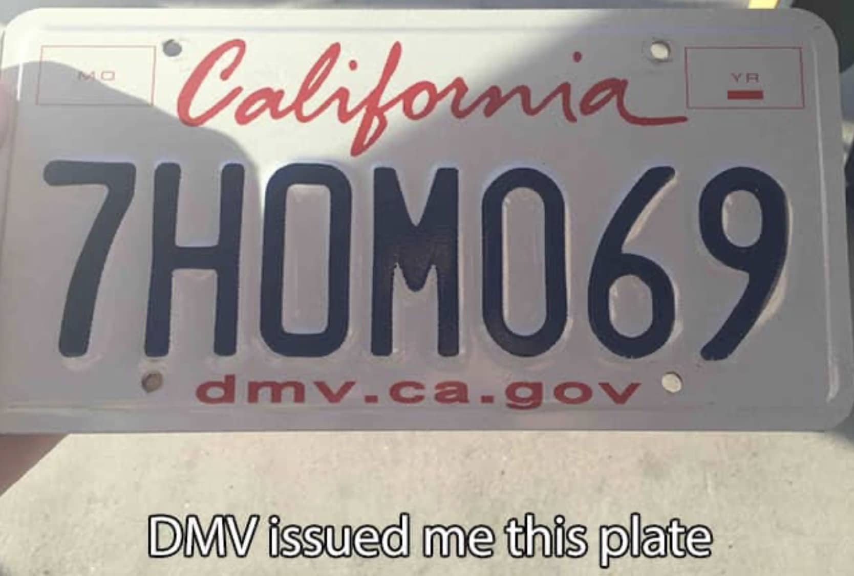 California license plate reading 7HOM069 with a caption stating the DMV issued this plate.