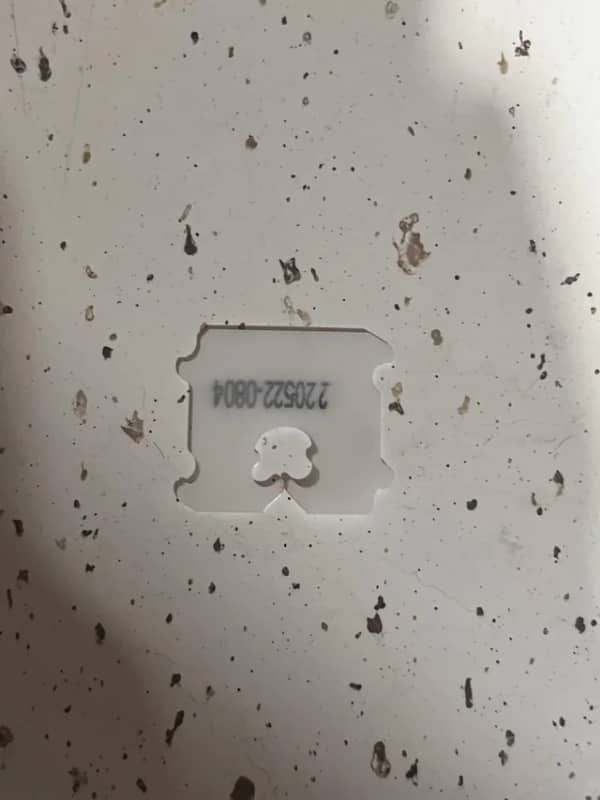 A small white plastic bread tag sitting inside a matching square cutout on a kitchen surface.