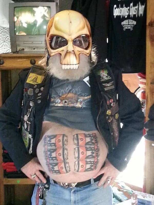 Biker wearing a skull mask showing off a tattoo of a Duff Beer six-pack.