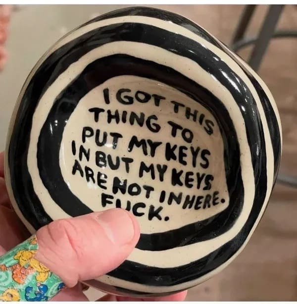 Hand holding a ceramic key bowl with a funny inscription about missing keys inside.
