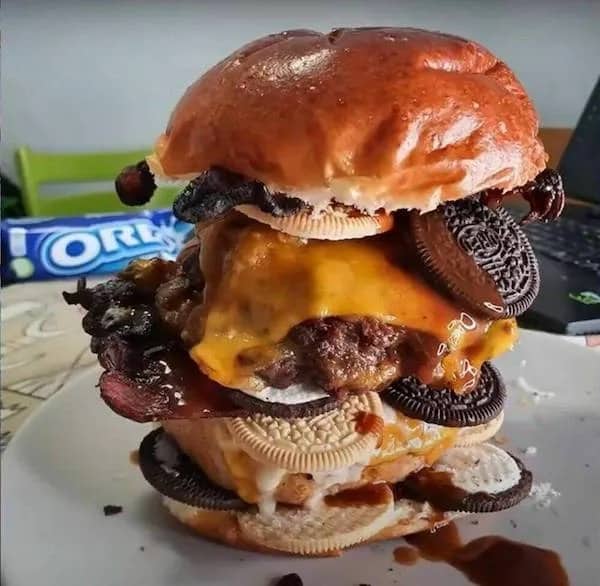 Cursed food image of a massive double cheeseburger stacked with chocolate Oreo cookies.