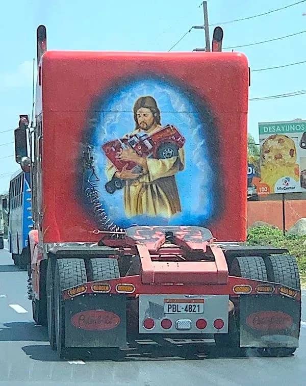 Bizarre truck mural depicting Jesus Christ gently cradling a small red pickup truck like a baby.
