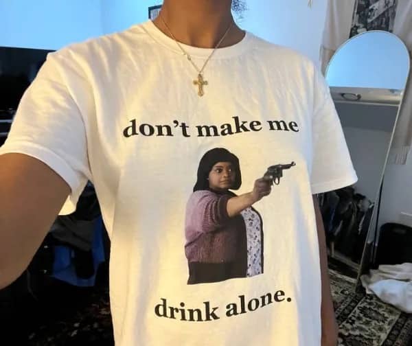 Person wearing white graphic tee featuring Octavia Spencer holding gun with funny movie quote.