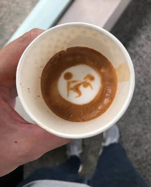 Overhead view of latte art in a coffee cup inadvertently looking like an explicit stick figure scene.