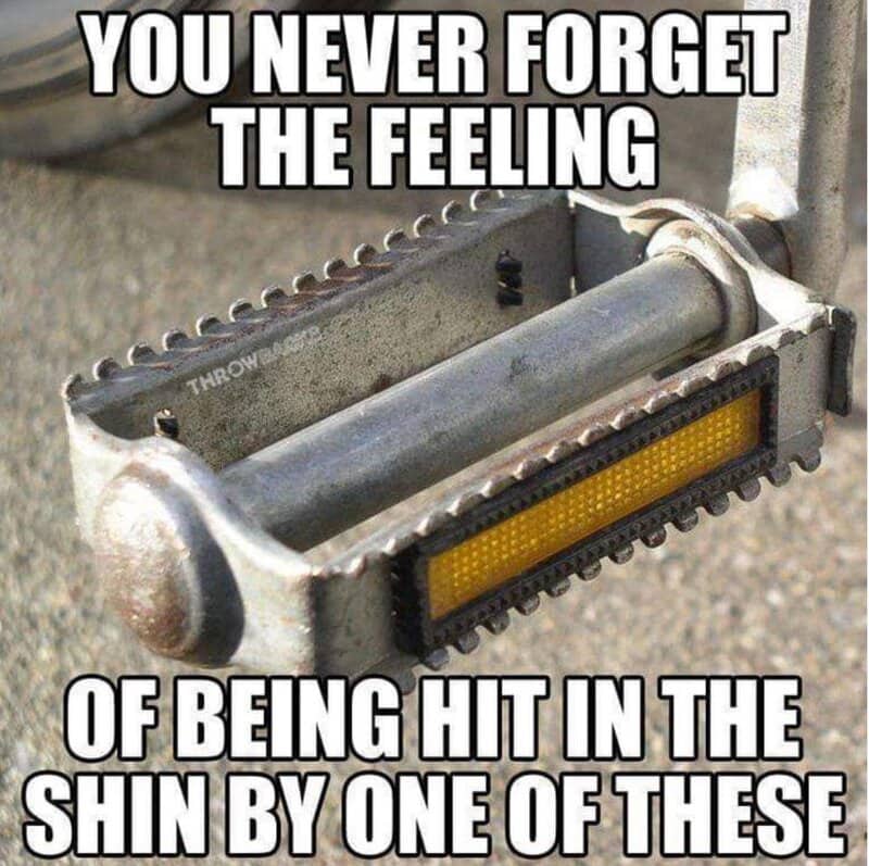 Close-up of a serrated metal bicycle pedal with a yellow safety reflector on the side.