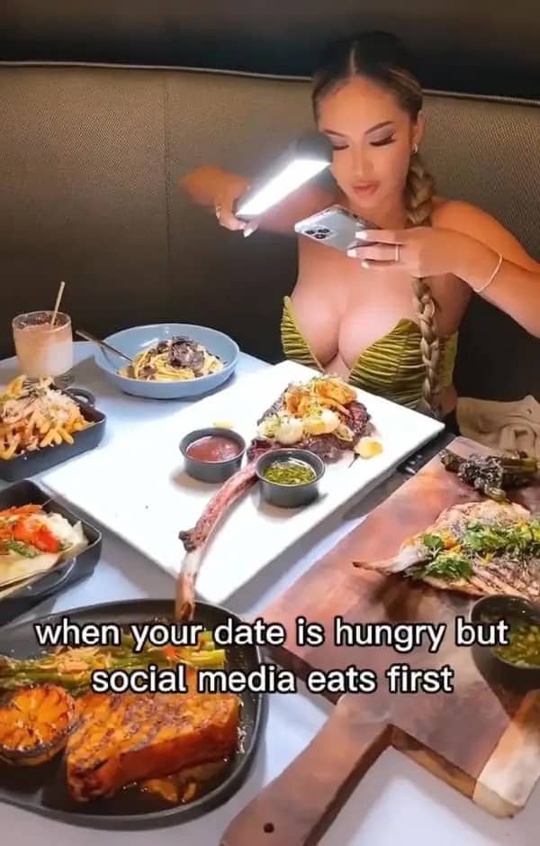 Woman holding a studio light bar over a fancy restaurant dinner table for a photo.