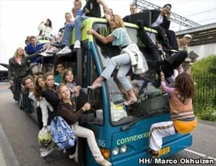 Dozens of passengers clinging frantically to the outside of a moving bus for public transit memes.
