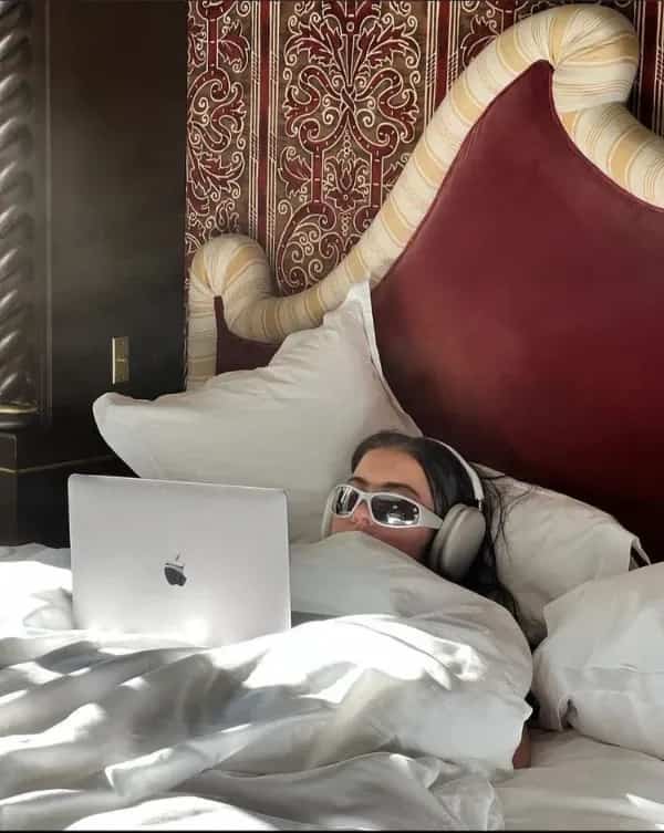Funny working from home meme showing a woman tucked in bed wearing futuristic sunglasses.