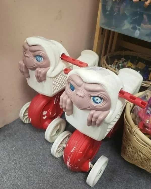 Vintage red plastic ET ride-on tricycle toys lined up on the floor.